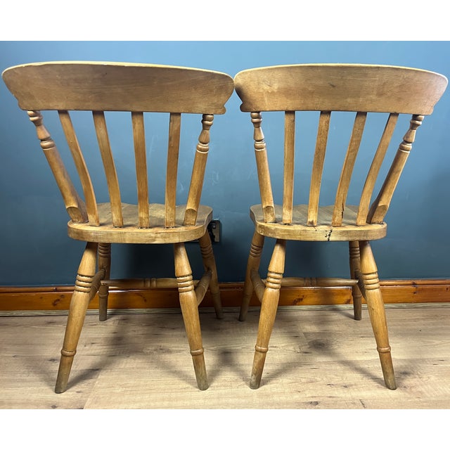 Beautiful vintage pair of chairs in a farmhouse-style beech dining design. They are often referred to as slat-back or...