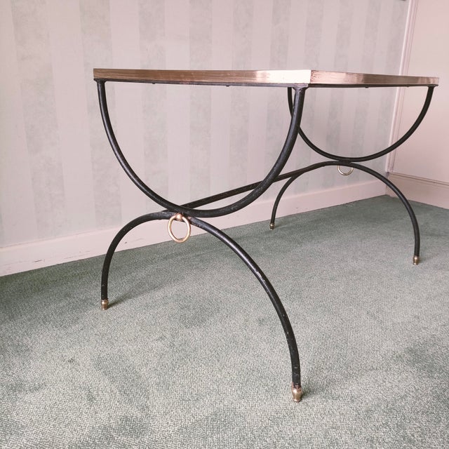 In the style of Jacques Adnet. Black metal base with a cross-shaped support adorned with a gold ring, smoked black glass top