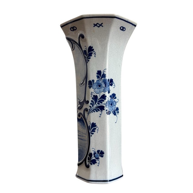 This particular vase, with its hexagonal shape and hand-painted romantic scene, aligns with the aesthetic of Delftware...