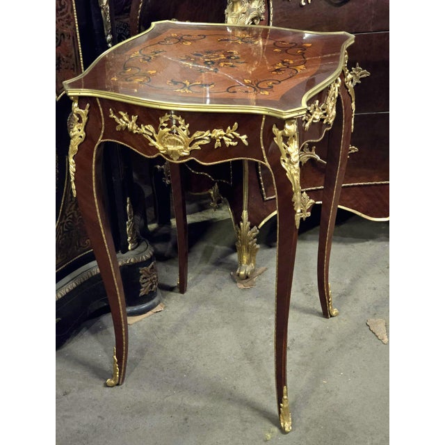 Elegant French-style side table featuring a sophisticated glass top that beautifully showcases the decorative artwork...