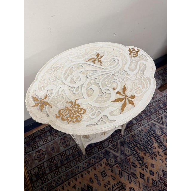 Charming cast iron outdoor table featuring a lovely decorative design, finished in white paint with elegant gilt...