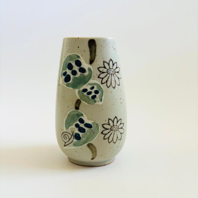 A mid century pottery vase. Tapered oval shaped. Matte light gray speckled glaze with a lovely painted design of leaves...