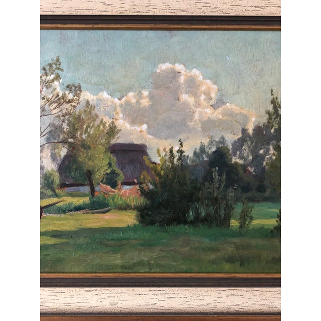 An antique original oil painting of a countryside landscape with a cottage from around 1925. The painting shows a cottage...