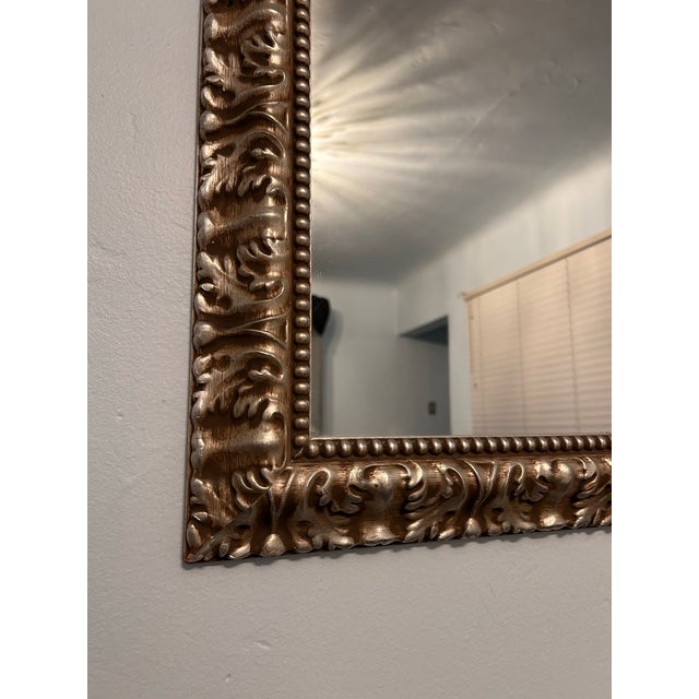 Ornate vine details carved into a large square gilt frame with a beaded border. This mantle mirror is stunning and stately...