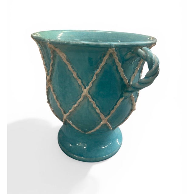 This decorative cachepot or urn features a vibrant, high-gloss turquoise glaze that gives it a rich, Mediterranean feel....