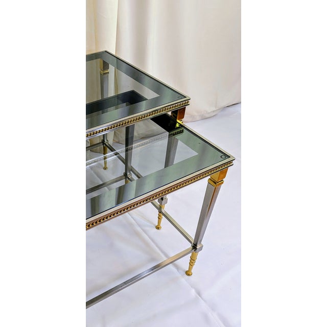 Two Steel and Brass Maison Baguès Style Nesting Tables 20th century, each with a rectangular smoked glass top, largest to...