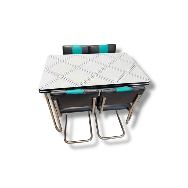 Description: Vintage retro metal dinette set featuring a white enamel-style tabletop with sleek black geometric line...