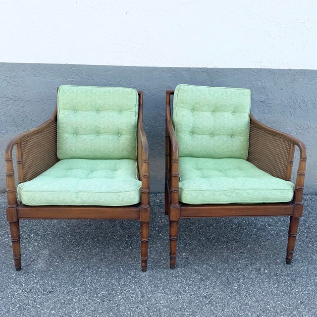 A stylish pair of vintage Hollywood Regency lounge chairs showcasing elegant faux bamboo frames with woven cane side and...