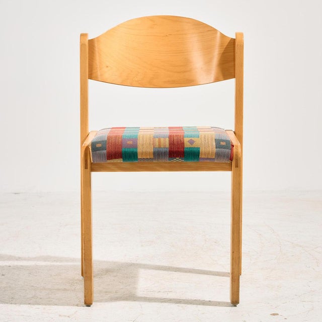 Stackable beech chair with textile seat from the 1980s. The surface of the chair has scratches, stains and wear in places.