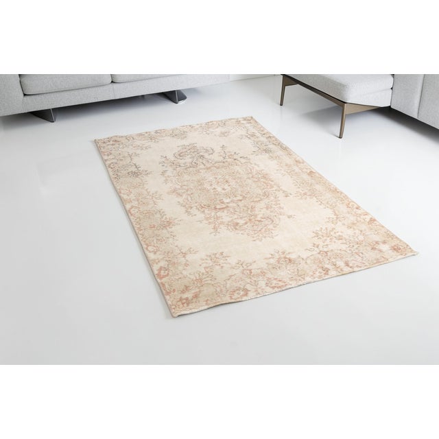 This is a vintage Turkish Oushak rug from the Mid 20th Century. The piece was hand-knotted.