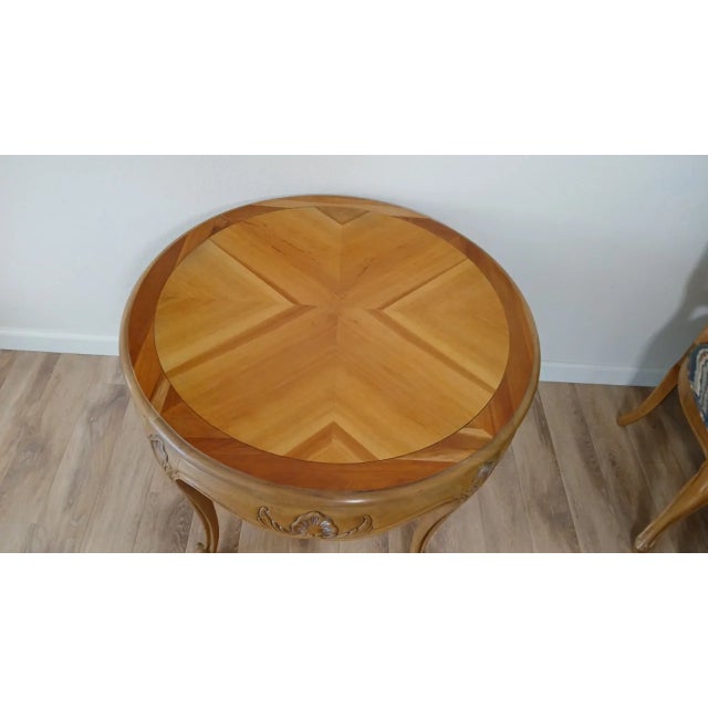 Country French side table. Light walnut finish. Features wood construction in a medium brown, floral carvings, inlaid top...