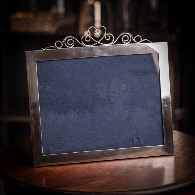 Antique 20th century american solid silver photograph frame of rectangular form, topped with applied wire scrollwork and a...