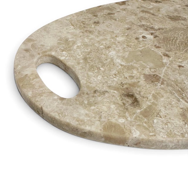 Carved from natural mineral, this oval board is smooth to the touch and rich in cream tones: marbled, veined, and striated...