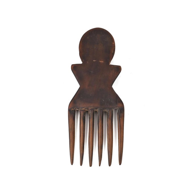 A delicately carved comb with a figure standing as the handle. Figural combs of this kind are common among people of...