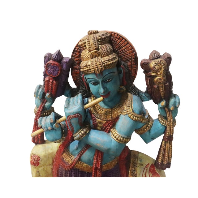Contemporary Indian Carved and Painted Wood Krishna Statue, in a typical pose sitting upon Nandi, and playing his flute....
