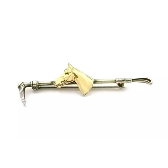 This vintage equestrian piece is crafted from 10k yellow gold, it features a horse and riding whip tie pin. A safety clasp...