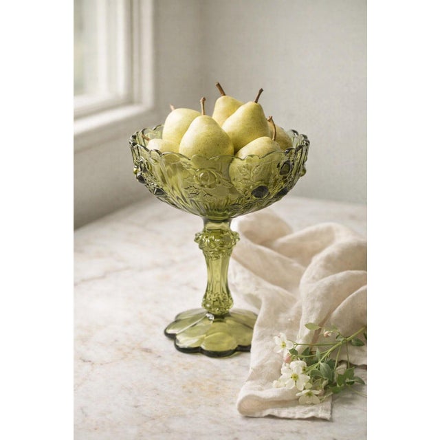 A charming mid-century pressed glass compote in a refined olive green hue, featuring an all-over floral motif and softly...