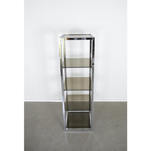 A freestanding shelving unit from the 1970s, reminiscent of designs by Milo Baughman. A square, chrome-plated metal frame...