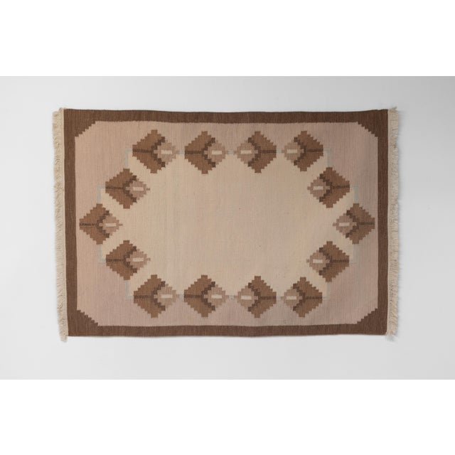 Mid-Century Swedish kilim in tones of browns and creams with a plain central field and geometric pattern. Minor staining....