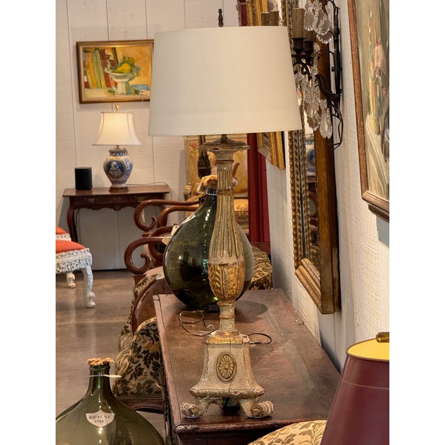 A carved and gilded wood altar stick converted to a lamp. The shaft is carved with vertical fluting and a band of leaves...