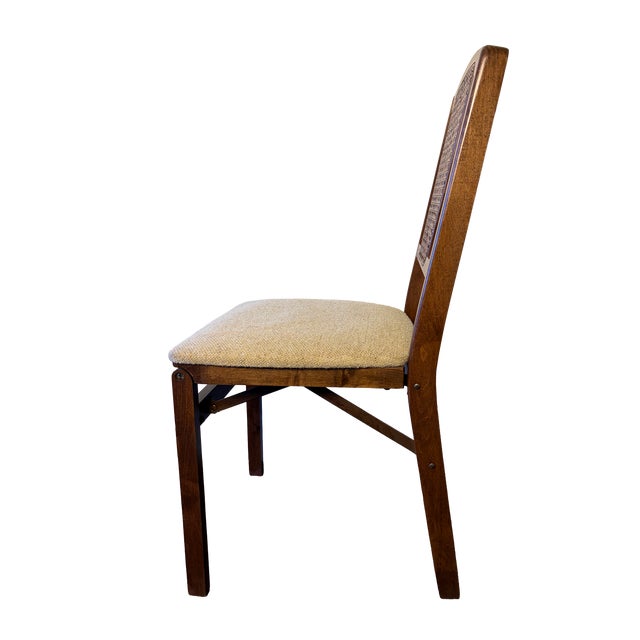 Vintage Stakmore folding chair featuring a warm wood frame, inset woven cane back and softly textured neutral upholstered...