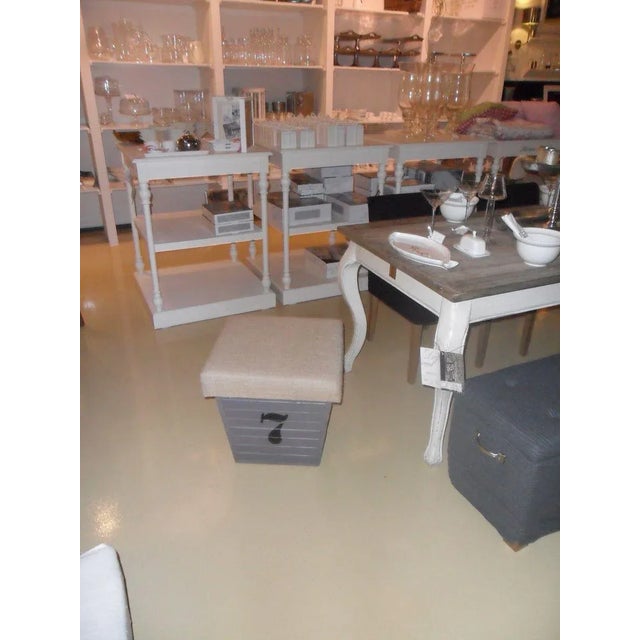 Storage box made of pine, which has been painted gray with the number 7 on its side. The lid is covered in sackcloth....