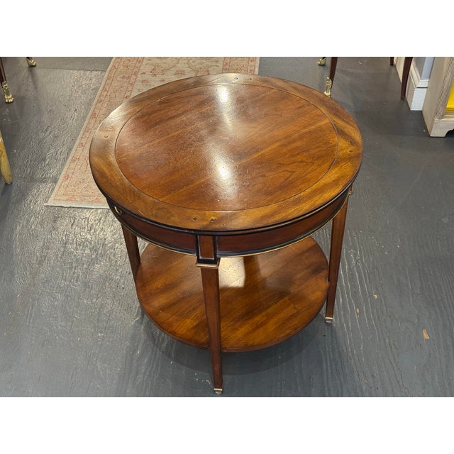 This is a Sherrill Occasional mahogany center table. It has black ebony banding and gold accents. It has a shelf at the...