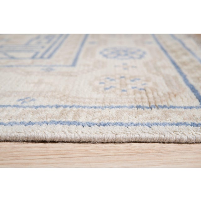 A hand-knotted wool rug, made in India and measuring 6' x 9'. Floral drawing carried across the field inside a traditional...