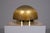 Table lamp consisting of a thick, textured glass dome supported by a circular solid brass base, the upper part honey-...