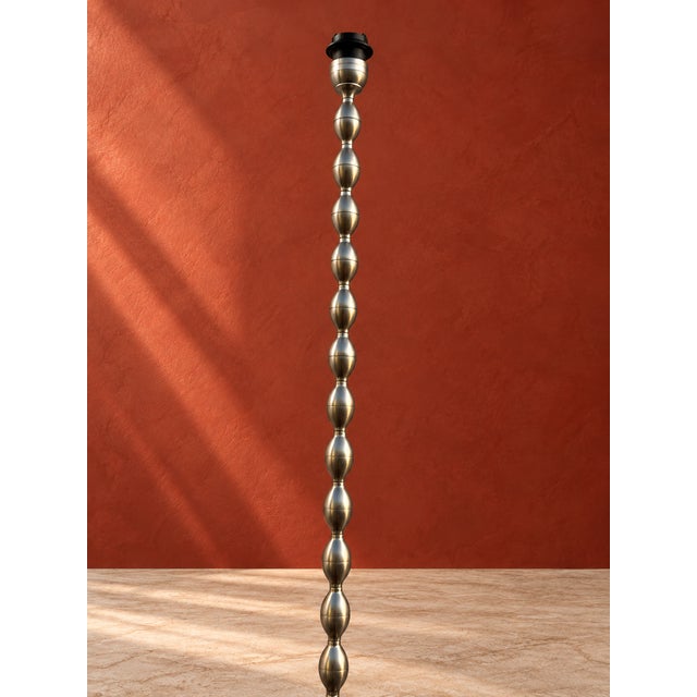 An elegant sculptural floor lamp distinguished by its slender vertical silhouette and rhythmic arrangement of elongated...