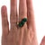 A 14k yellow gold ring featuring three green onyx stones. The band is elegantly curved, holding the stones in a prong...