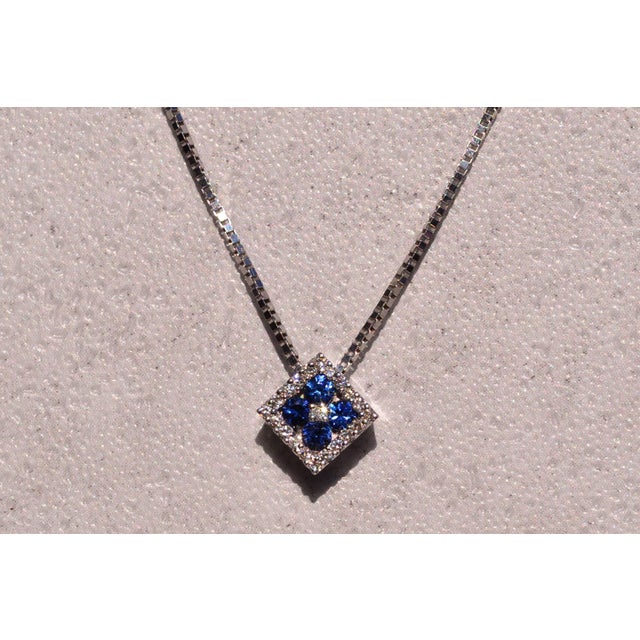 The 135th Street: Sapphire and Diamond Halo Necklace in White Gold. The necklace centers on a round diamond above a series...