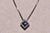 The 135th Street: Sapphire and Diamond Halo Necklace in White Gold. The necklace centers on a round diamond above a series...