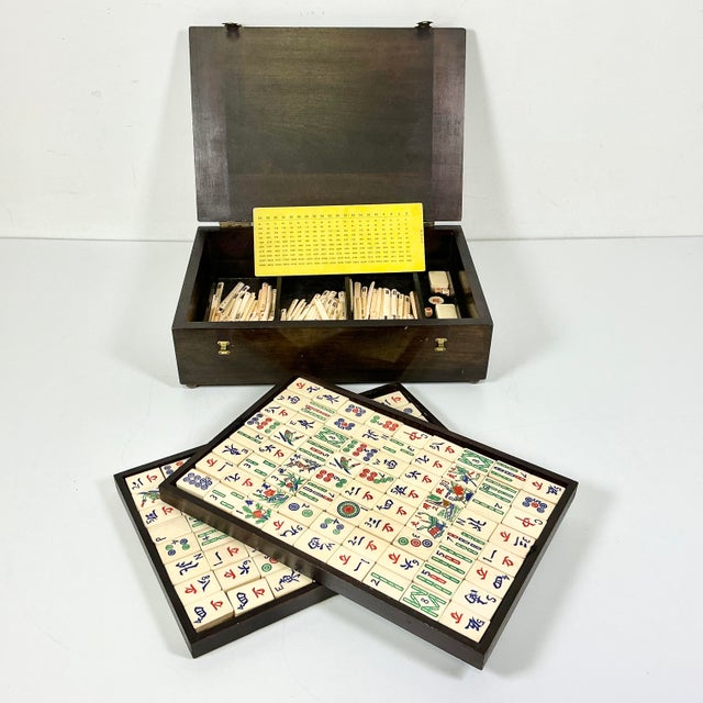 This is a lovely antique Mahjong Game Set. It features tiles that have bamboo backs with bone fronts. The tiles are...