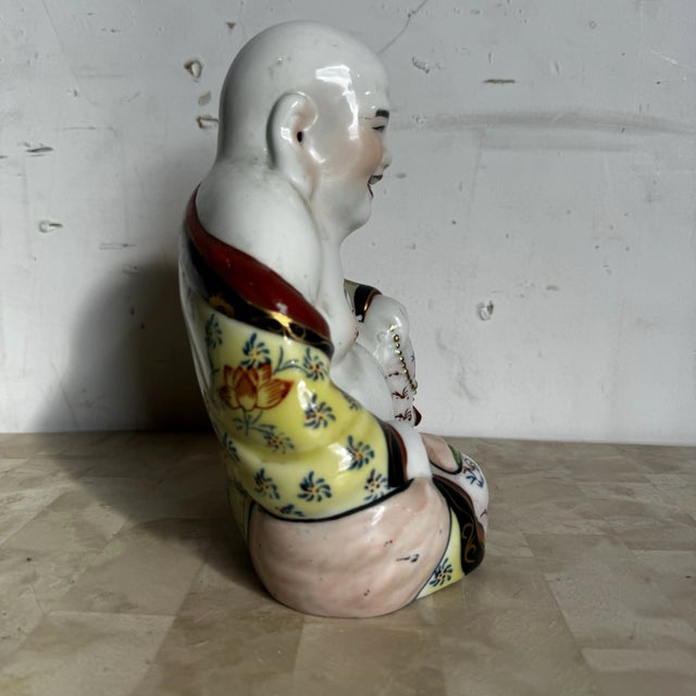 This Chinese hand painted porcelain Happy Buddha sculpture captures the joyful spirit and symbolic abundance associated...