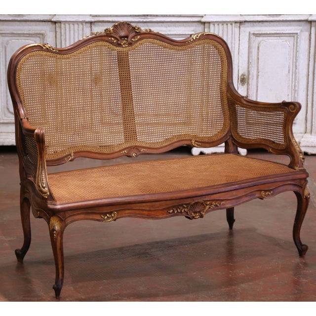 Elegant and finely detailed, this French Louis XV style settee was crafted circa 1920 from richly patinated walnut with...