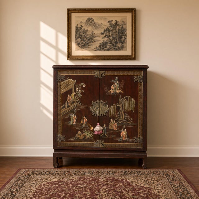 An artisan-crafted Qing dynasty style cabinetry adorned with carved figures and hand-painted landscapes against an oxblood...