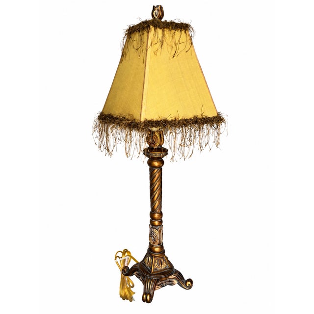 An ornate buffet-style table lamp featuring a slender barley-twist column, raised leaf and scroll motifs, and a sculptural...