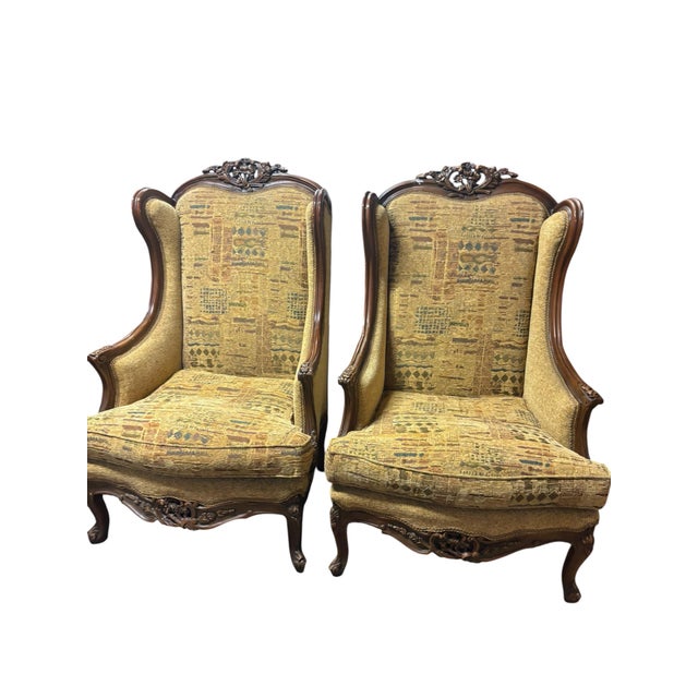 Bring timeless French elegance to your home with this exceptional pair of carved walnut bergère-style lounge chairs....