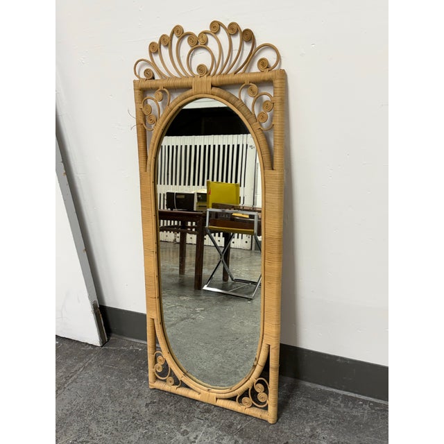 Design Plus Gallery presents a Vintage Scrollwork Rattan Wall Mirror. This mirror has a rectangular rattan frame...