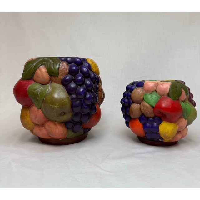 This pair of colorful fruit adorned pots are sure to add texture and color to your space! Hand painted ceramic vessels in...