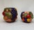 This pair of colorful fruit adorned pots are sure to add texture and color to your space! Hand painted ceramic vessels in...