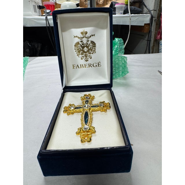 Beautiful vintage Fabergé jeweled cross featuring ornate gold-tone detailing, crystal embellishments, and deep blue...