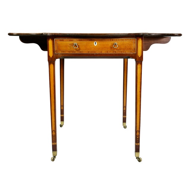 With rectangular top and serpentine drop leaves over a drawer raised on square tapered legs with casters.