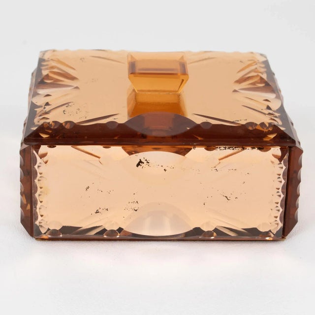 This lovely mirrored glass decorative box was crafted in the 1940s. The square design boasts pink peach-colored glass with...