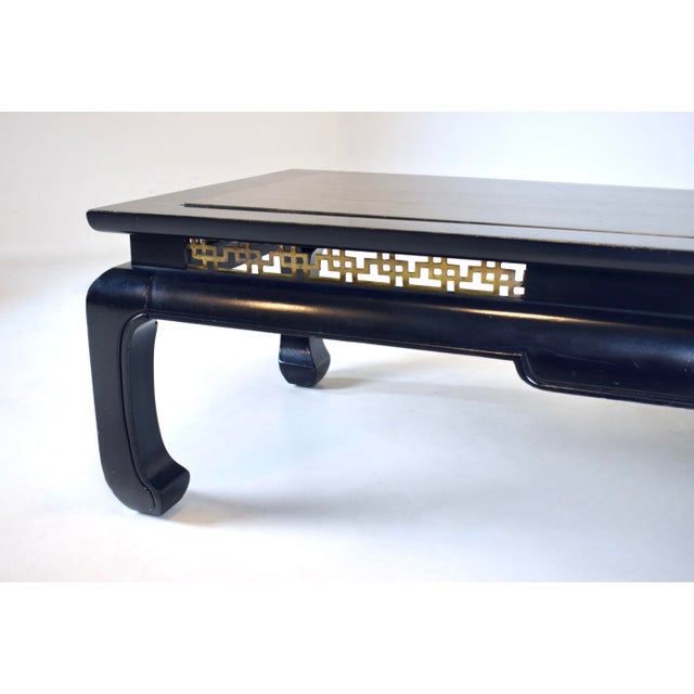 A mid 20th century black lacquered Ming style coffee table embellished with pierced brass fretwork just beneath the top...