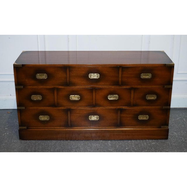 A handsome and functional campaign sideboard crafted in the mid-20th century, by Jansen of London. This elegant piece...