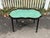 An antique black lacquered tole tray table with a scalloped-shaped edge, gilt trim along the rim and a hand-painted floral...