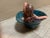 Whimsical pottery bowl with a reclining girl inside a blue bowl. Color is a deep aqua green blue. She is quite pink...