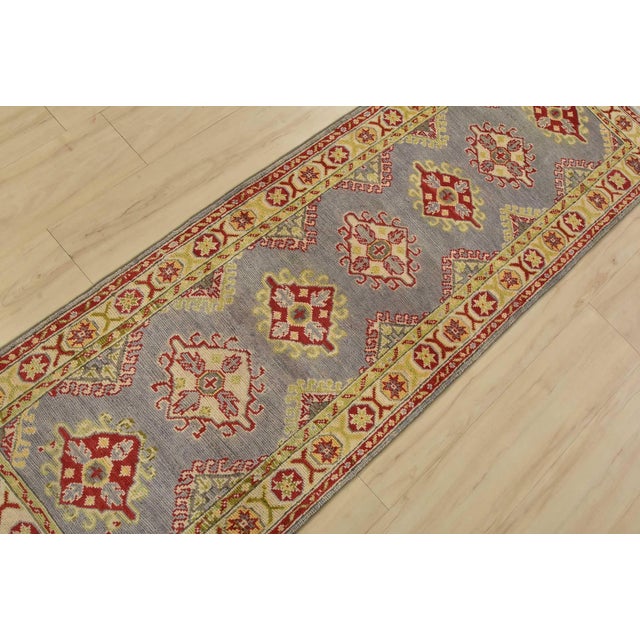 A tribal Caucasian Kazak runner hand-knotted with fine wool on a cotton foundation. This rug features a row of geometric...